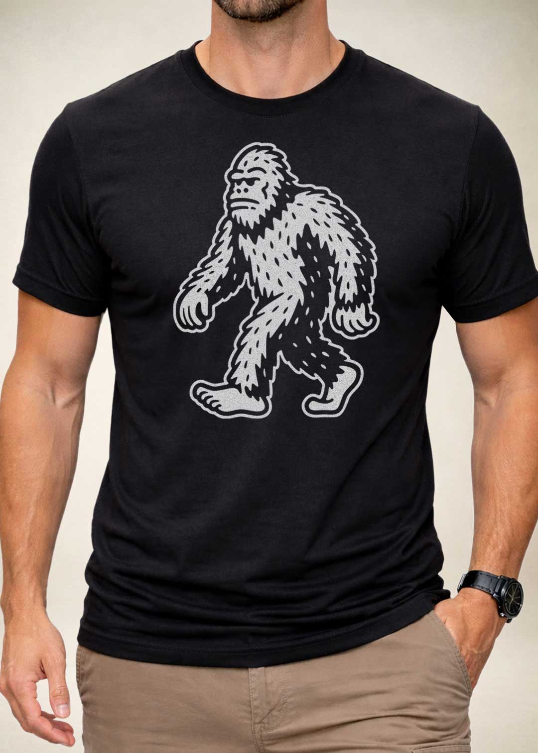 Black t-shirt with a white Bigfoot graphic worn by a person on a neutral background